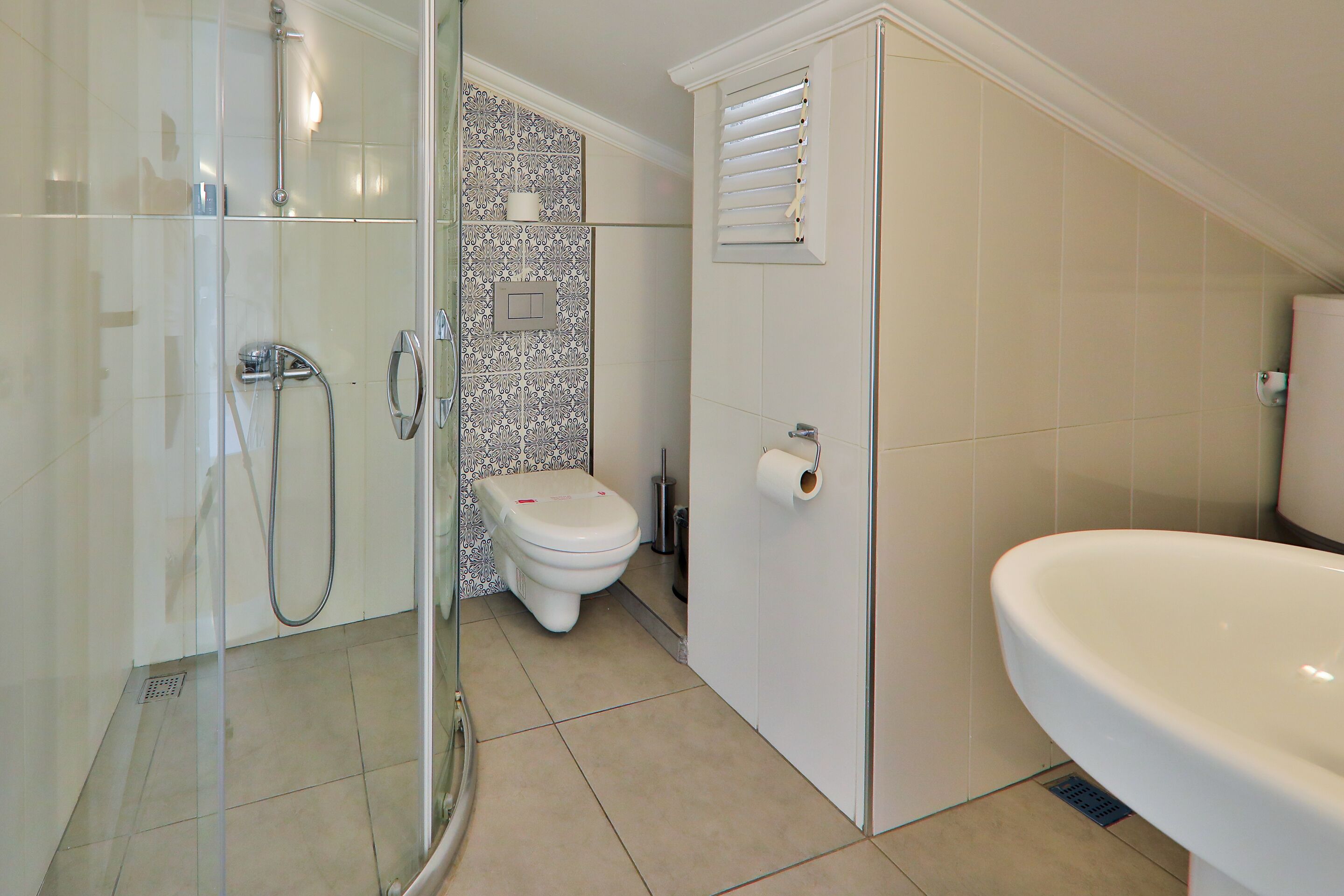 A bathroom with a glass-enclosed shower, a toilet, and a sink.