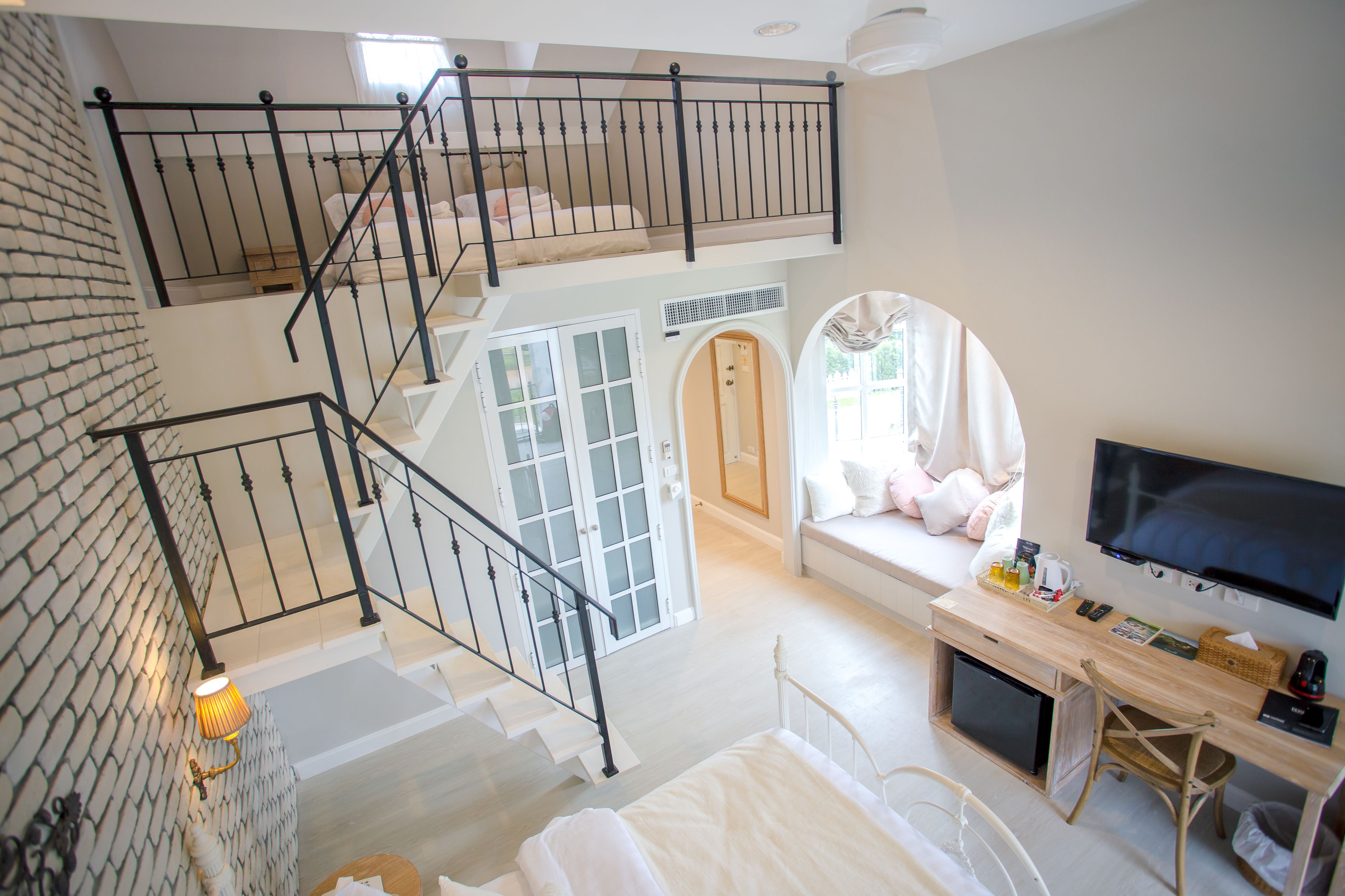 A multi-level interior with a staircase, a seating area with a television, and a desk with various items.