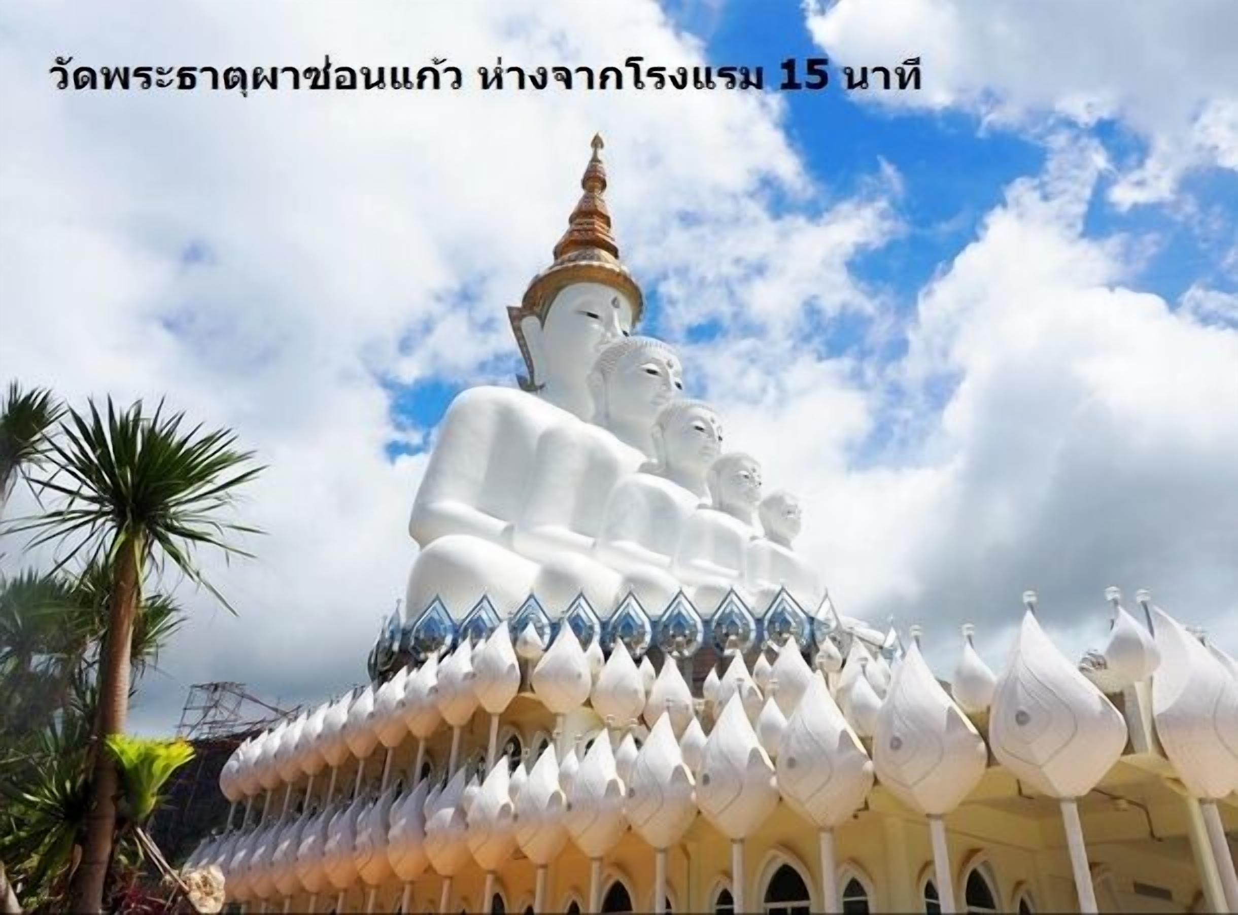A large white Buddha statue with a golden spire, surrounded by smaller statues and a row of white, lotus-shaped structures.