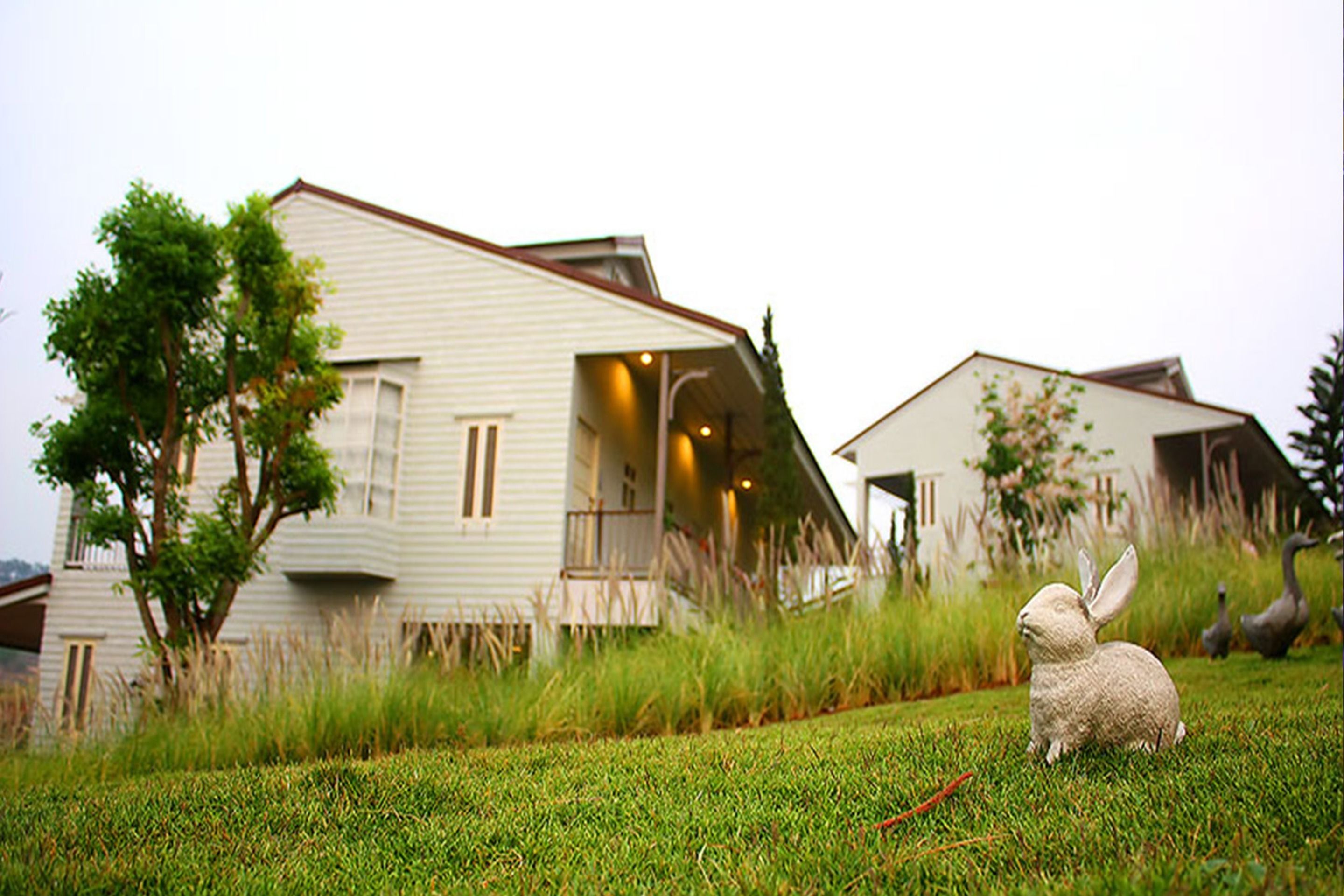 A house with a sloped roof and a front porch. There is a grassy area in front of the house.