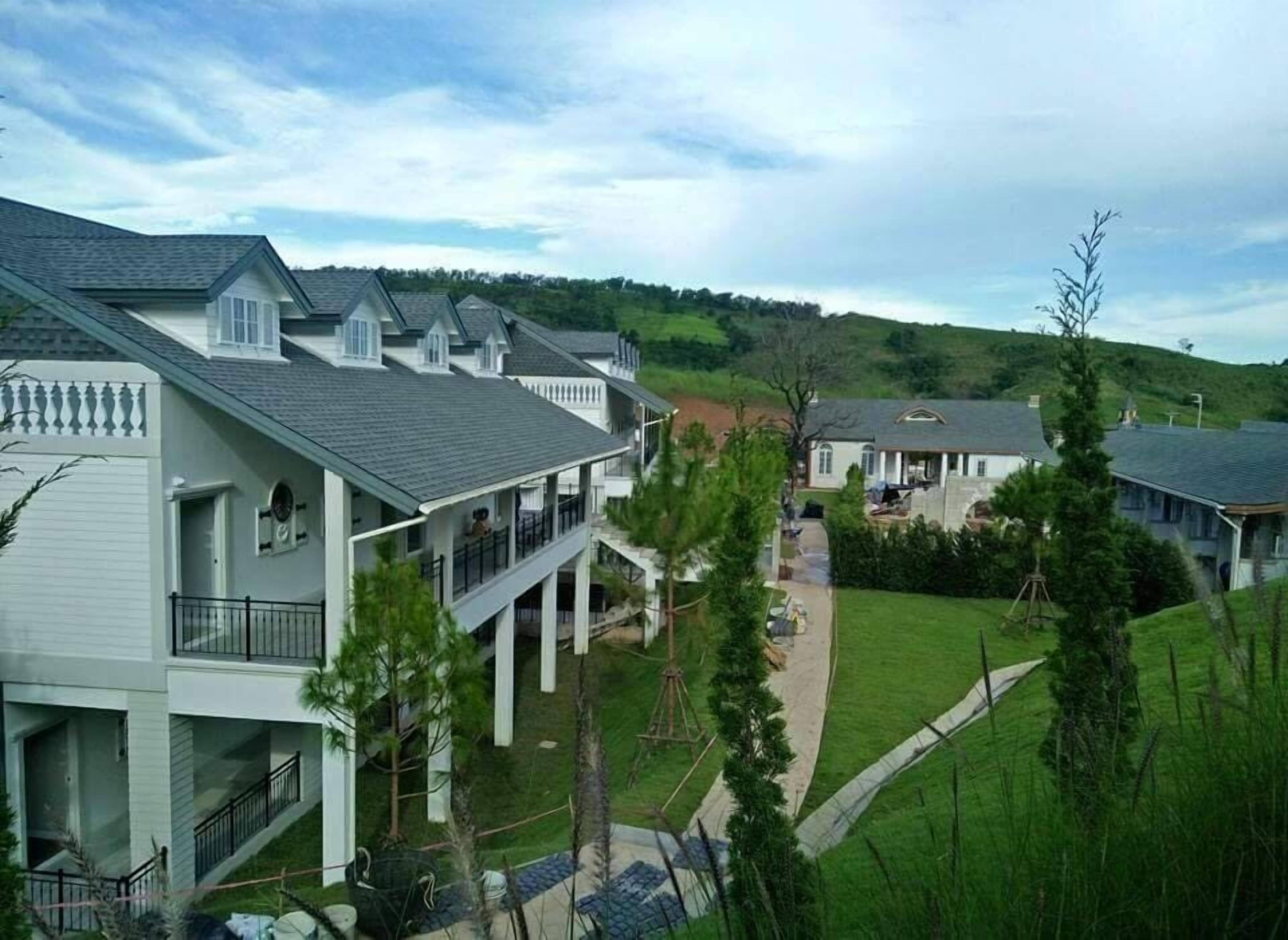 A residential area with multiple houses, a well-maintained lawn, and a clear sky.