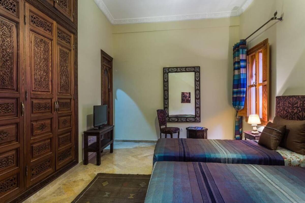 Una habitación con cama, televisión, espejo y armario.