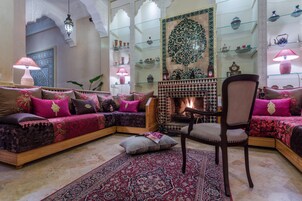 A traditional Moroccan interior with a sofa set, a wooden chair, and a patterned rug.