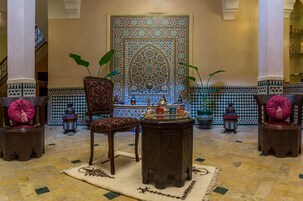Un interior tradicional con un muro estampado, una fuente central y muebles ornamentados.