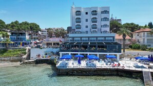 A waterfront restaurant with outdoor seating and a view of the sea. - Marti Beach Hotel (Kusadasi)