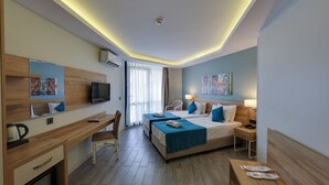 A hotel room with a desk, two beds, a television, and a window with curtains. - Marti Beach Hotel (Kusadasi)