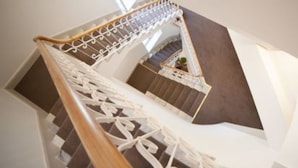 Un escalier en colimaçon avec une rampe blanche et un tapis marron.