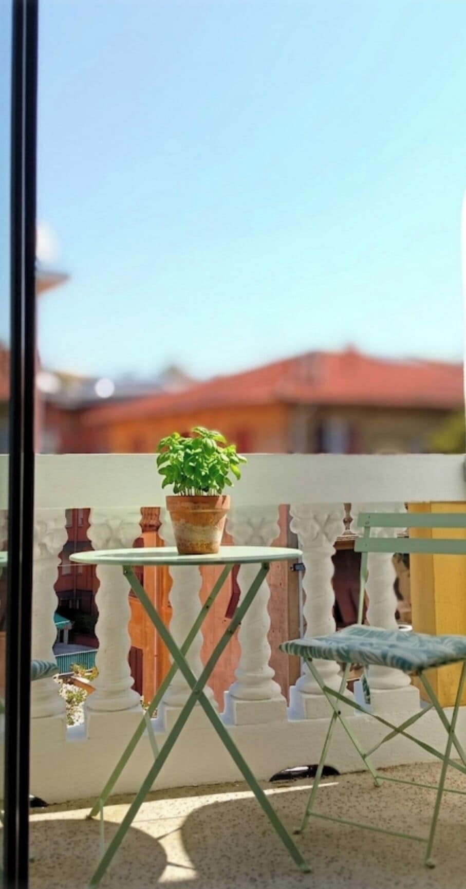 Un balcon avec un pot de fleurs, une table et une chaise.