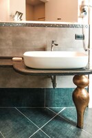 Un baño con lavamanos blanco, encimera oscura y azulejos verdes.