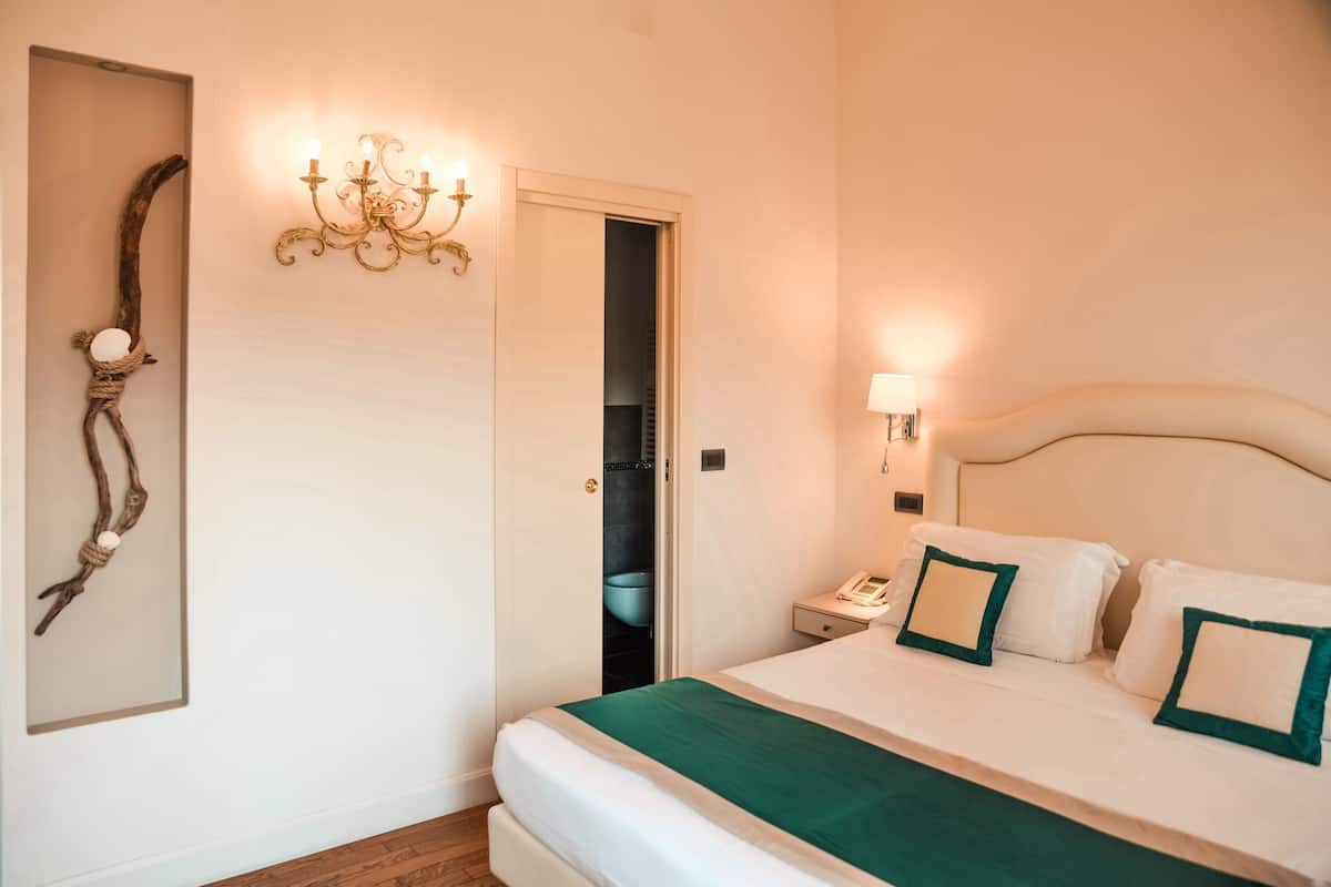 Une chambre à coucher bien rangée, avec un lit, une table de chevet, une lampe et un élément décoratif mural.