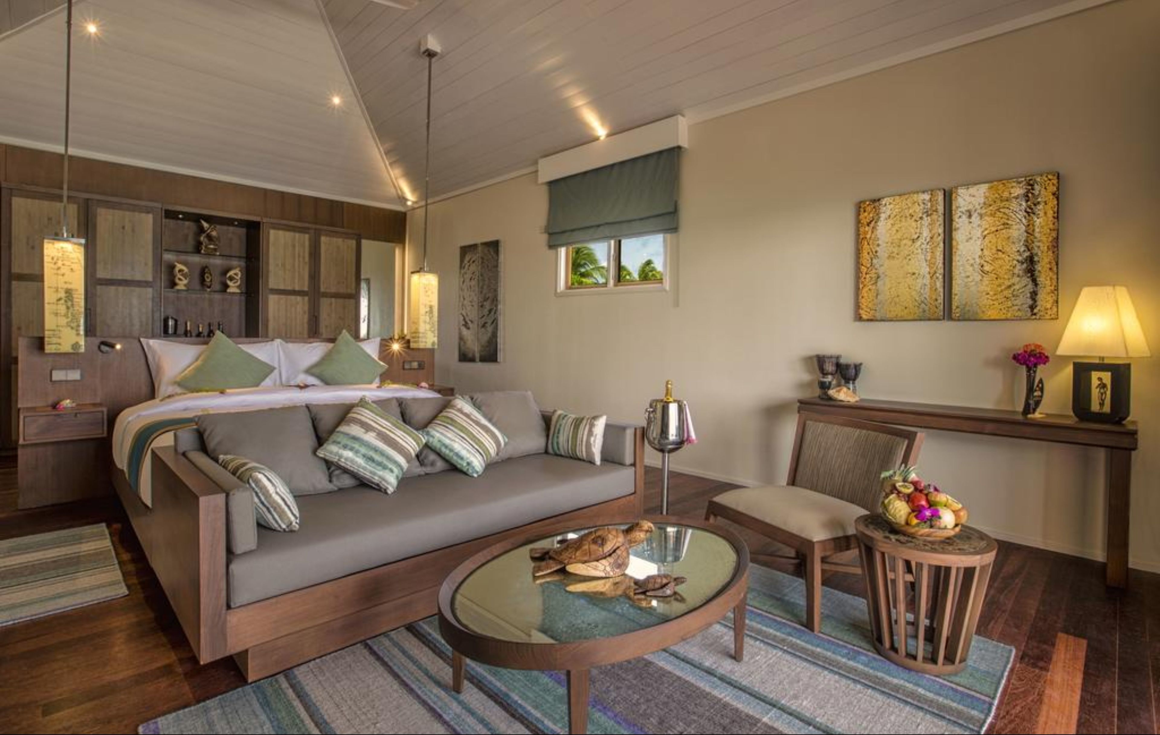 A modern bedroom with a large bed, a sofa, a round coffee table, and a small side table.