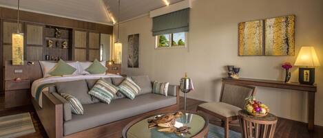 A modern bedroom with a large bed, a sofa, a round coffee table, and a small side table.