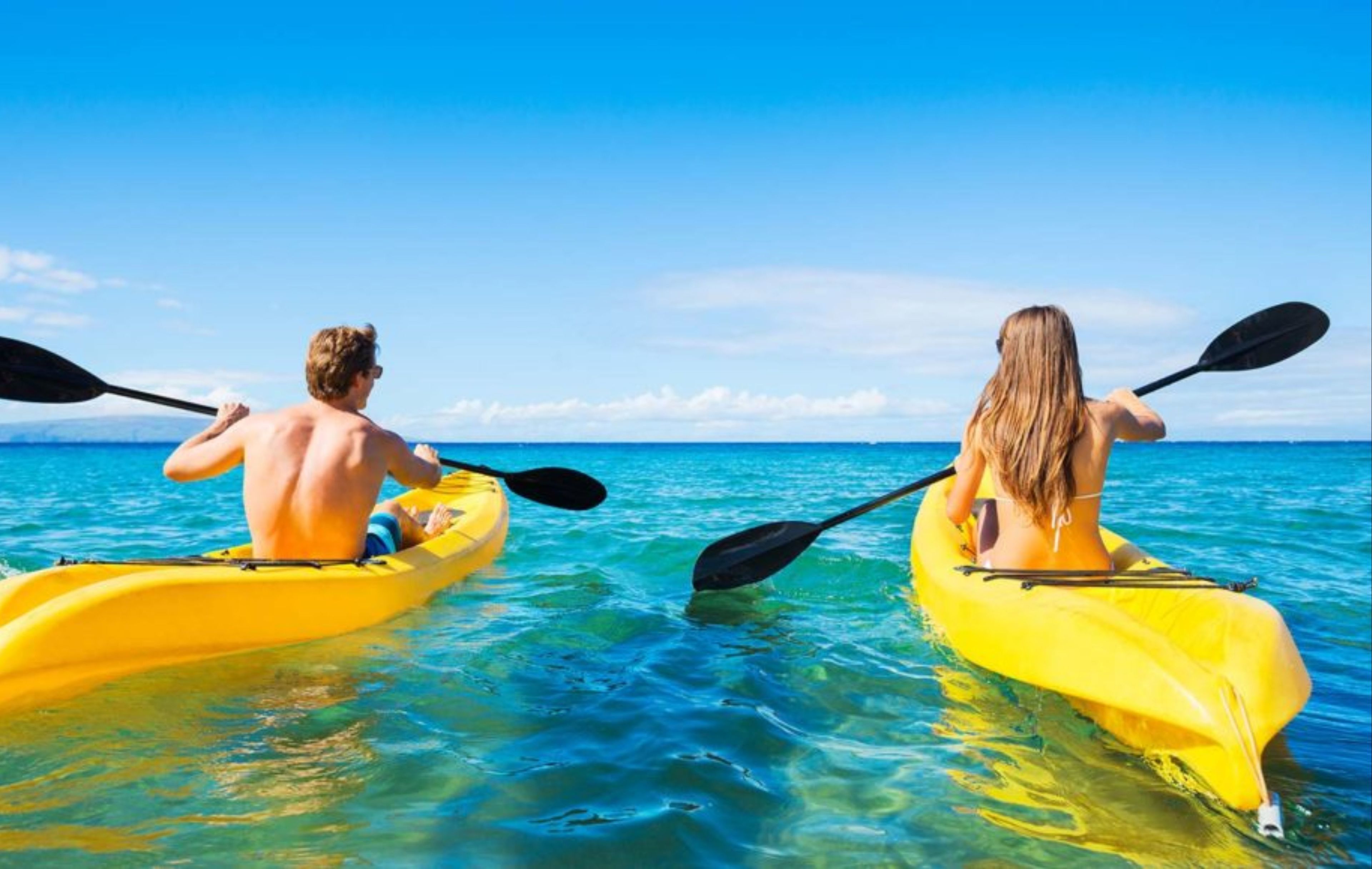 Two people kayaking on a clear blue sea.