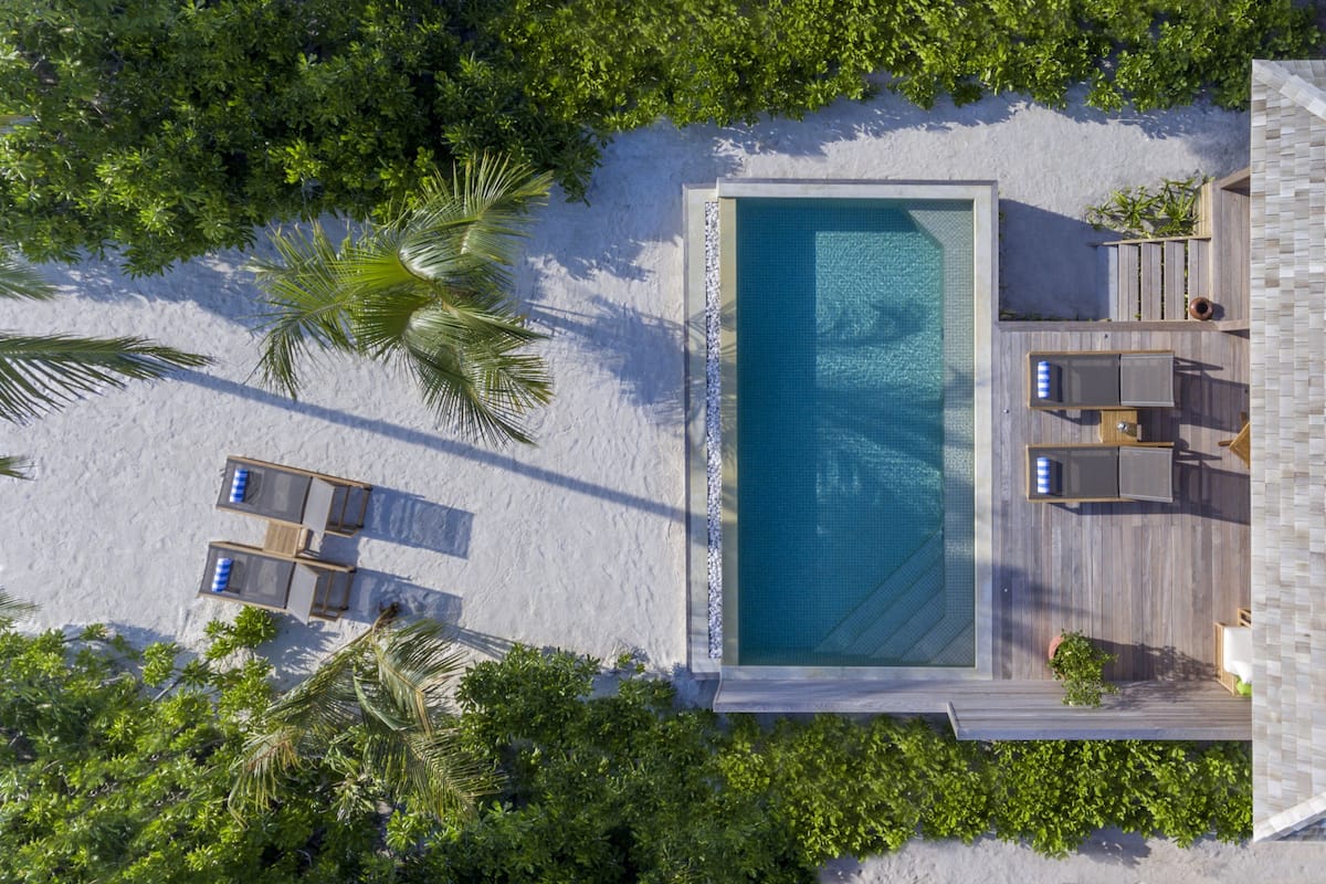 Luchtbeeld van een resort met een zwembad, ligbedden en een houten terras.