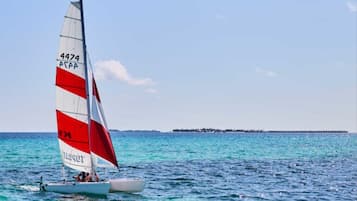 Un voilier avec une voile rouge et blanche sur une mer calme.