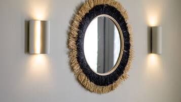 A wall-mounted mirror with a textured frame and two wall sconces on either side.
