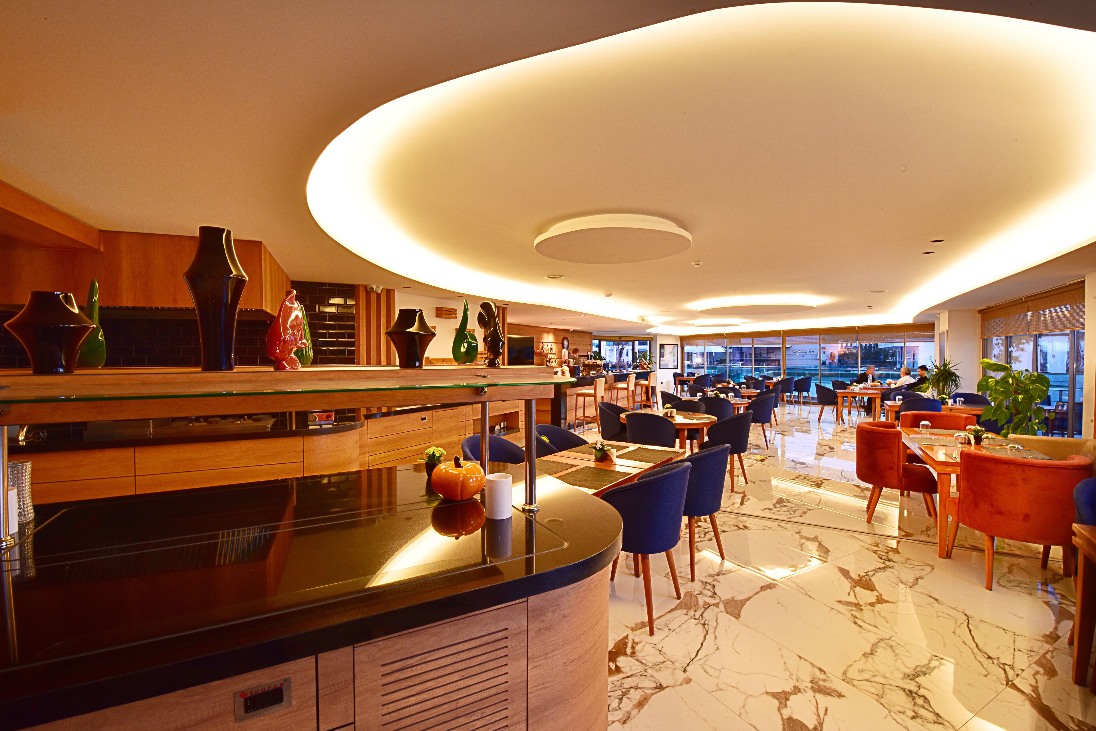 A modern hotel lobby with a curved ceiling, a central bar area, and seating arrangements.