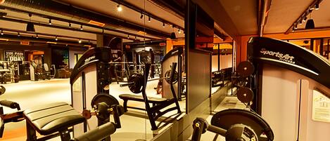 Un gimnasio con diverso equipo de ejercicio, incluyendo bancos y máquinas de pesas.