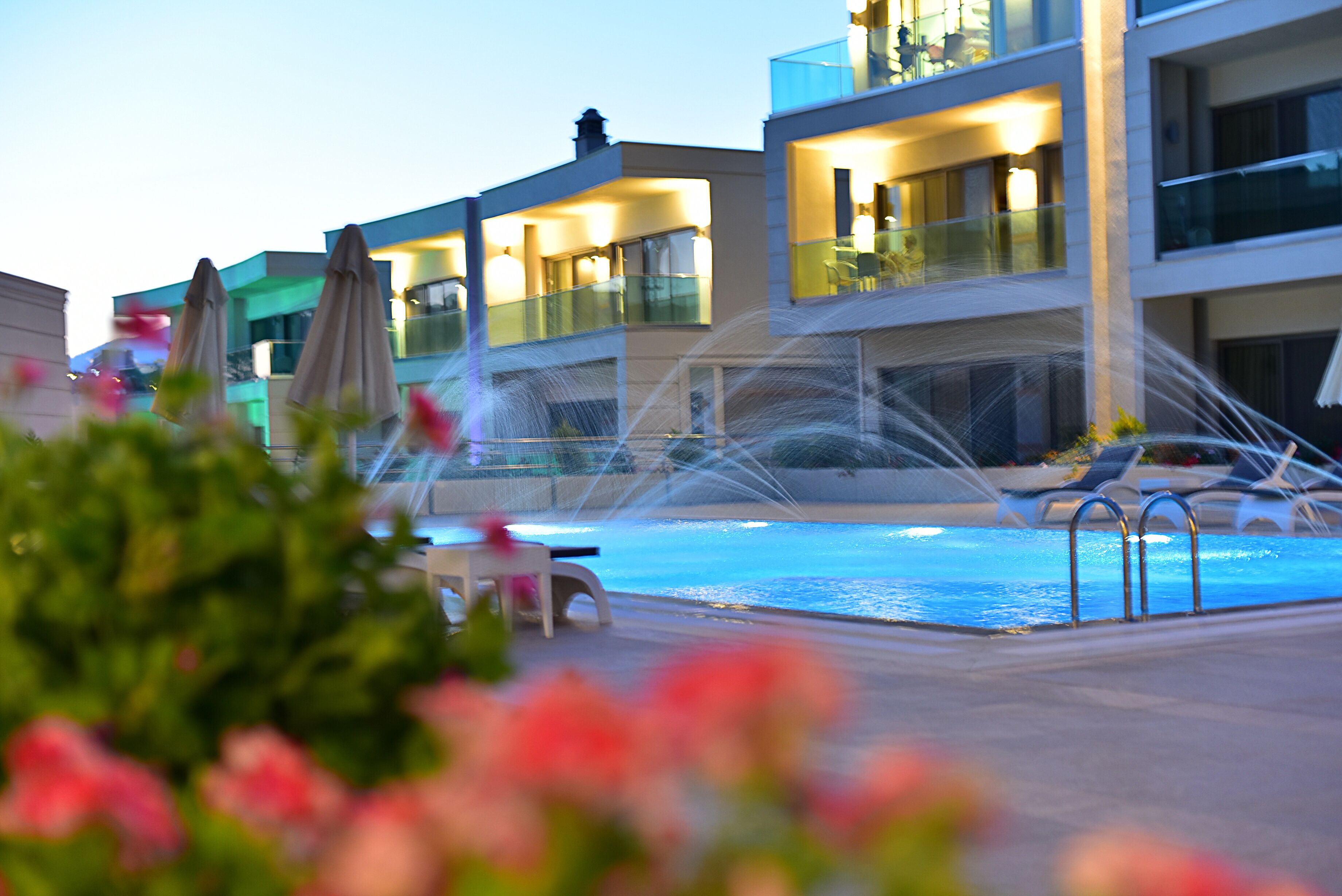 Un hôtel moderne doté d’une piscine, d’un espace extérieur aménagé et d’un élément décoratif aquatique.
