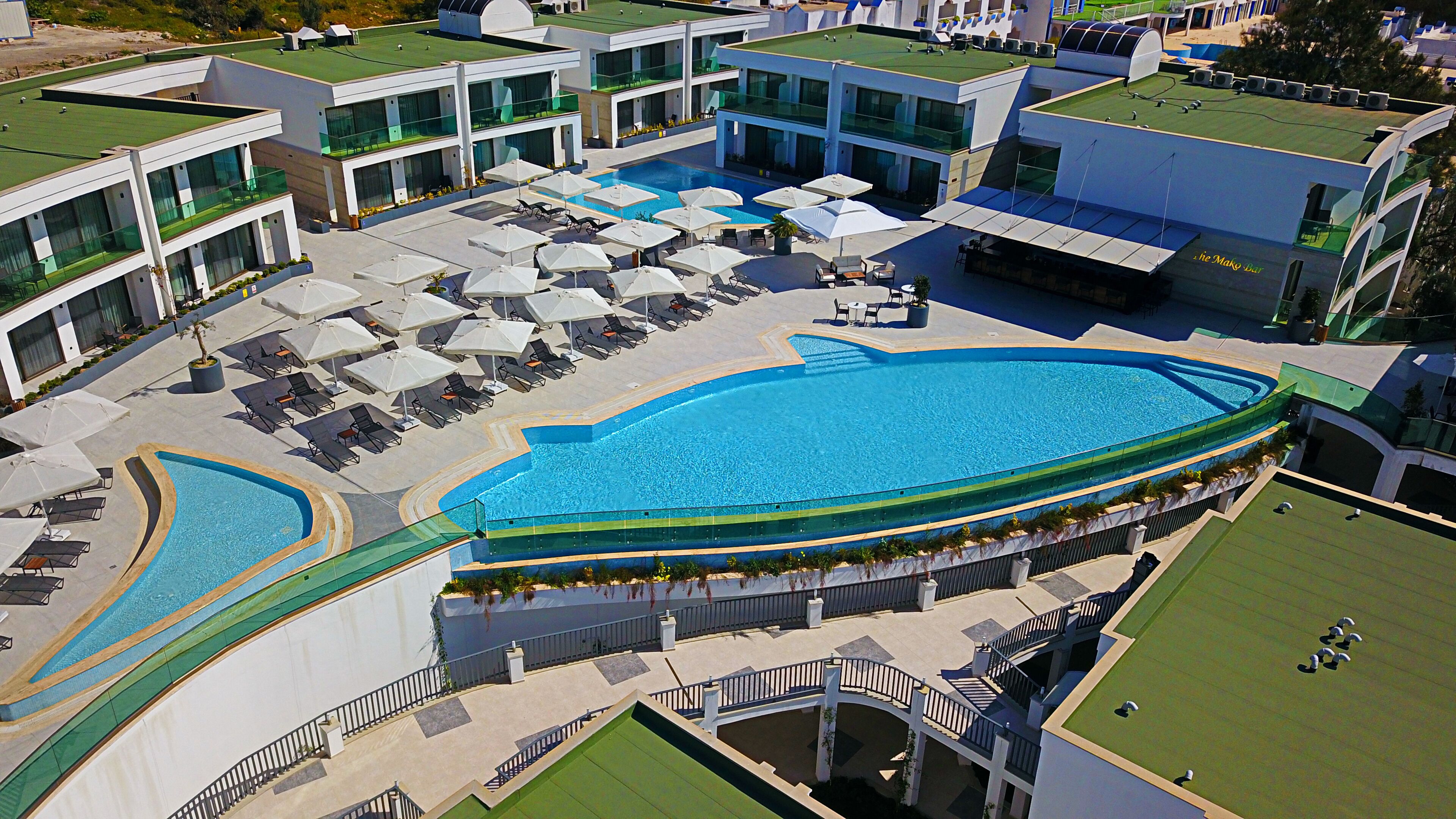 An aerial view of a hotel with a large central pool, multiple balconies, and outdoor seating areas.