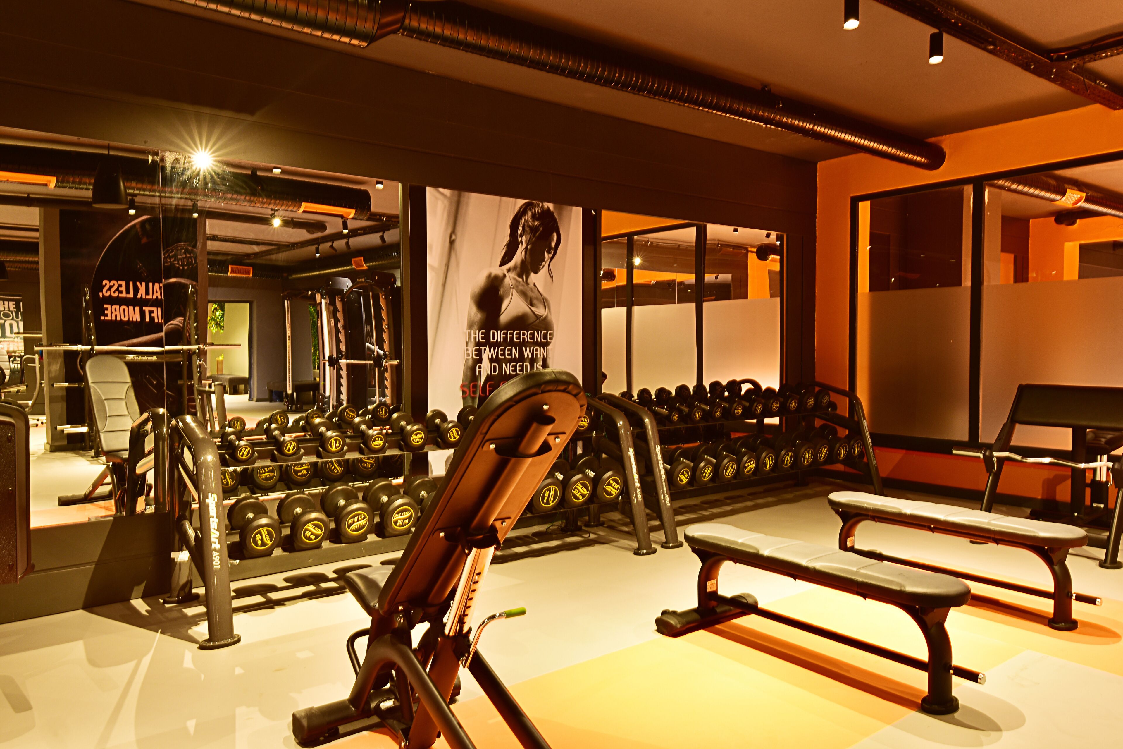 A gym with exercise equipment, benches, and dumbbells.