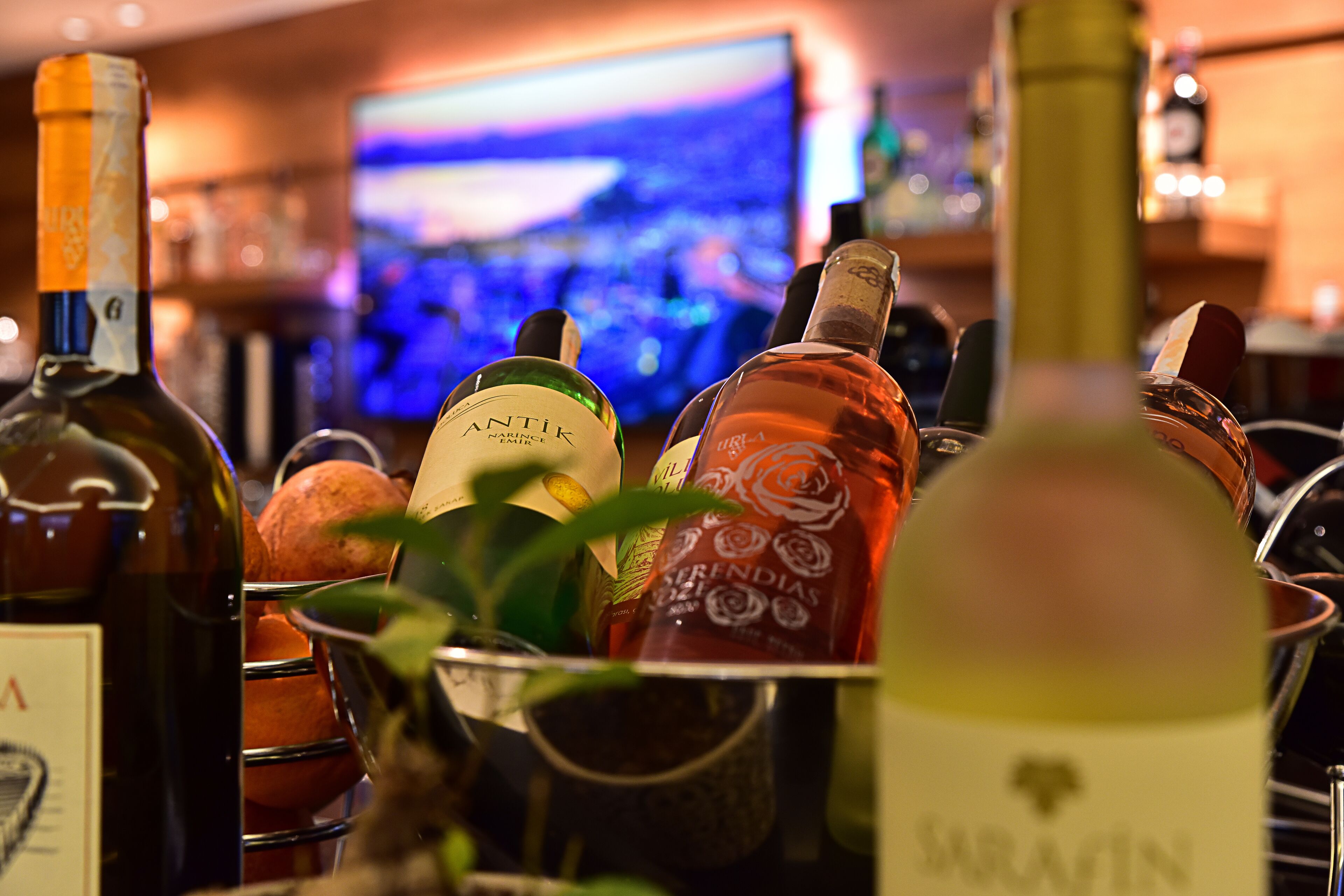 A bar area with bottles of wine and a television in the background.