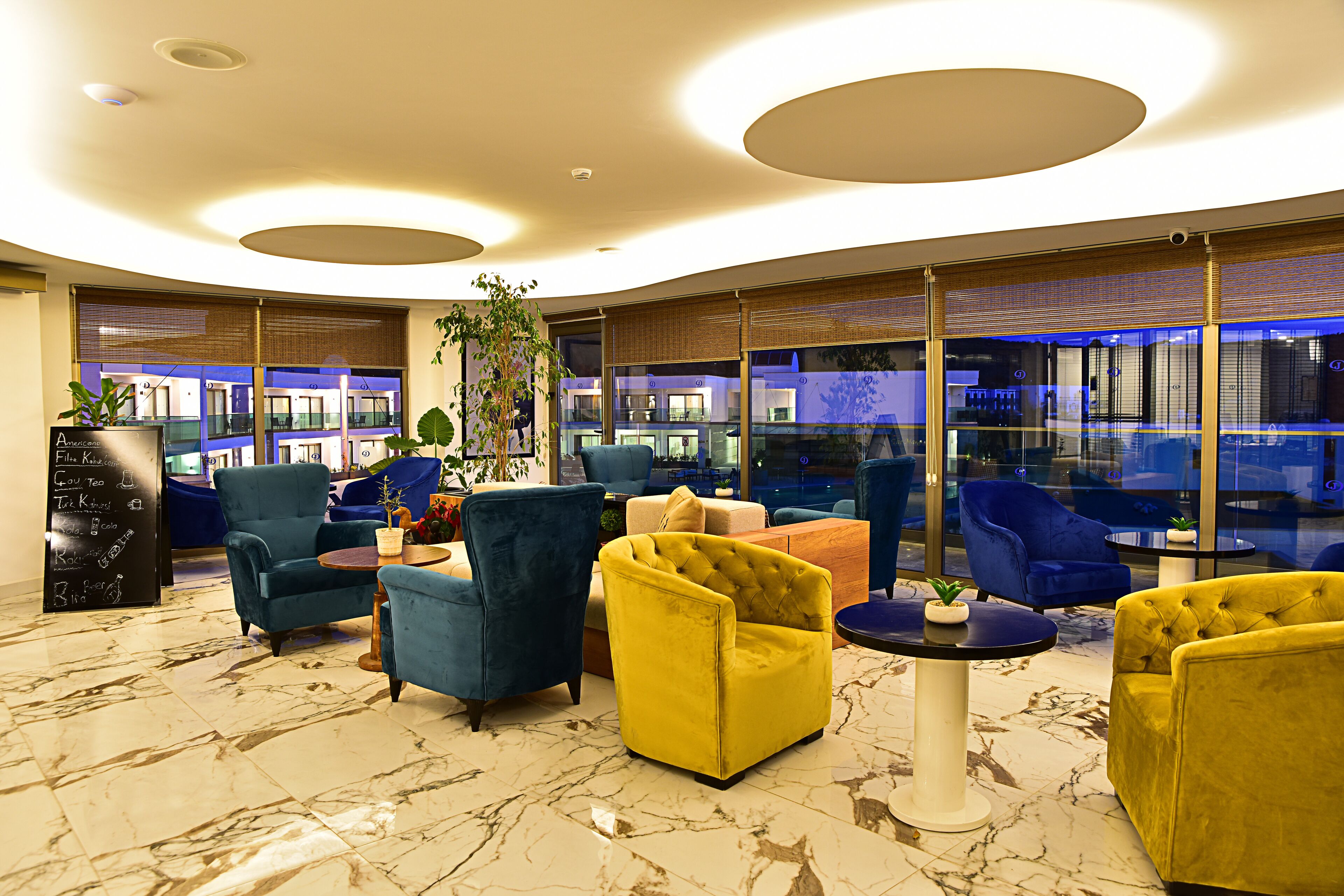 A modern lounge area with plush seating, a marble floor, and large windows offering views of the cityscape.