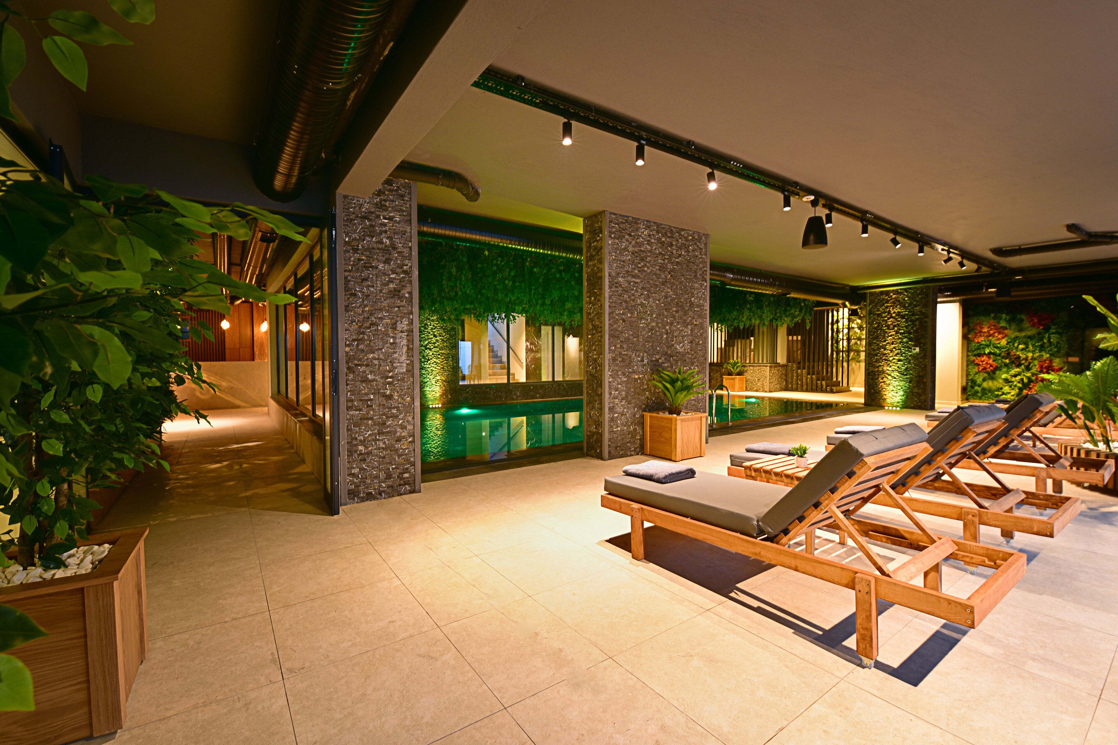 Et spa-område med træliggestole, en reception og en grøn væg med planter.