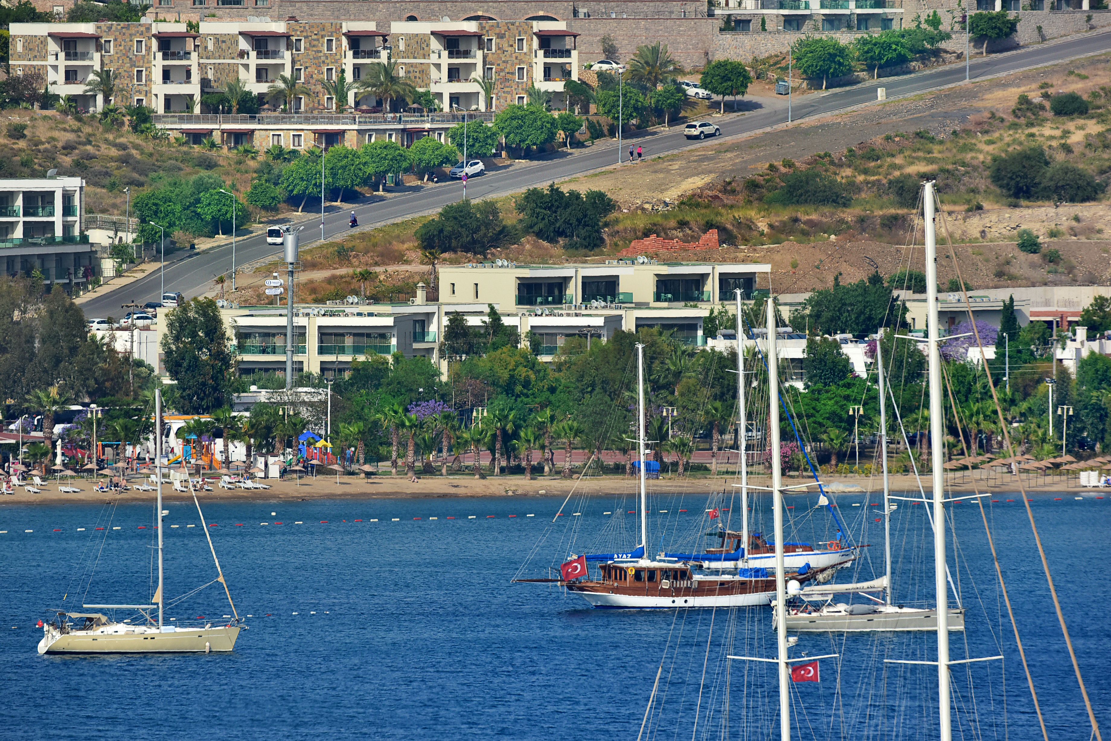 Un pueblo costero con un puerto deportivo, barcos y edificios con balcones que dan al agua.