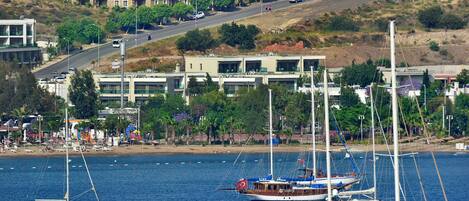 Un pueblo costero con un puerto deportivo, barcos y edificios con balcones que dan al agua.