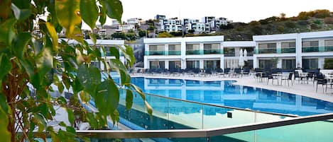 Un hôtel moderne doté d’une grande piscine, de nombreux balcons et offrant une vue sur les collines environnantes.