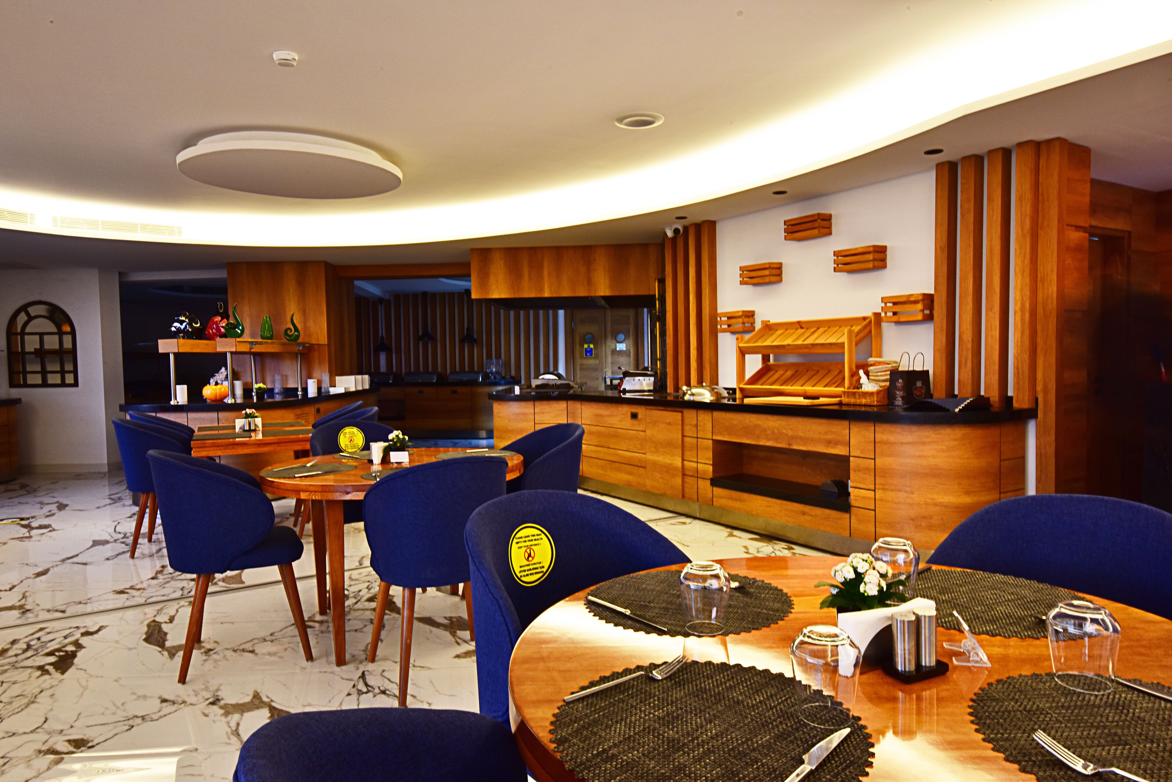 A modern dining area with a round table, blue chairs, and a wooden counter.