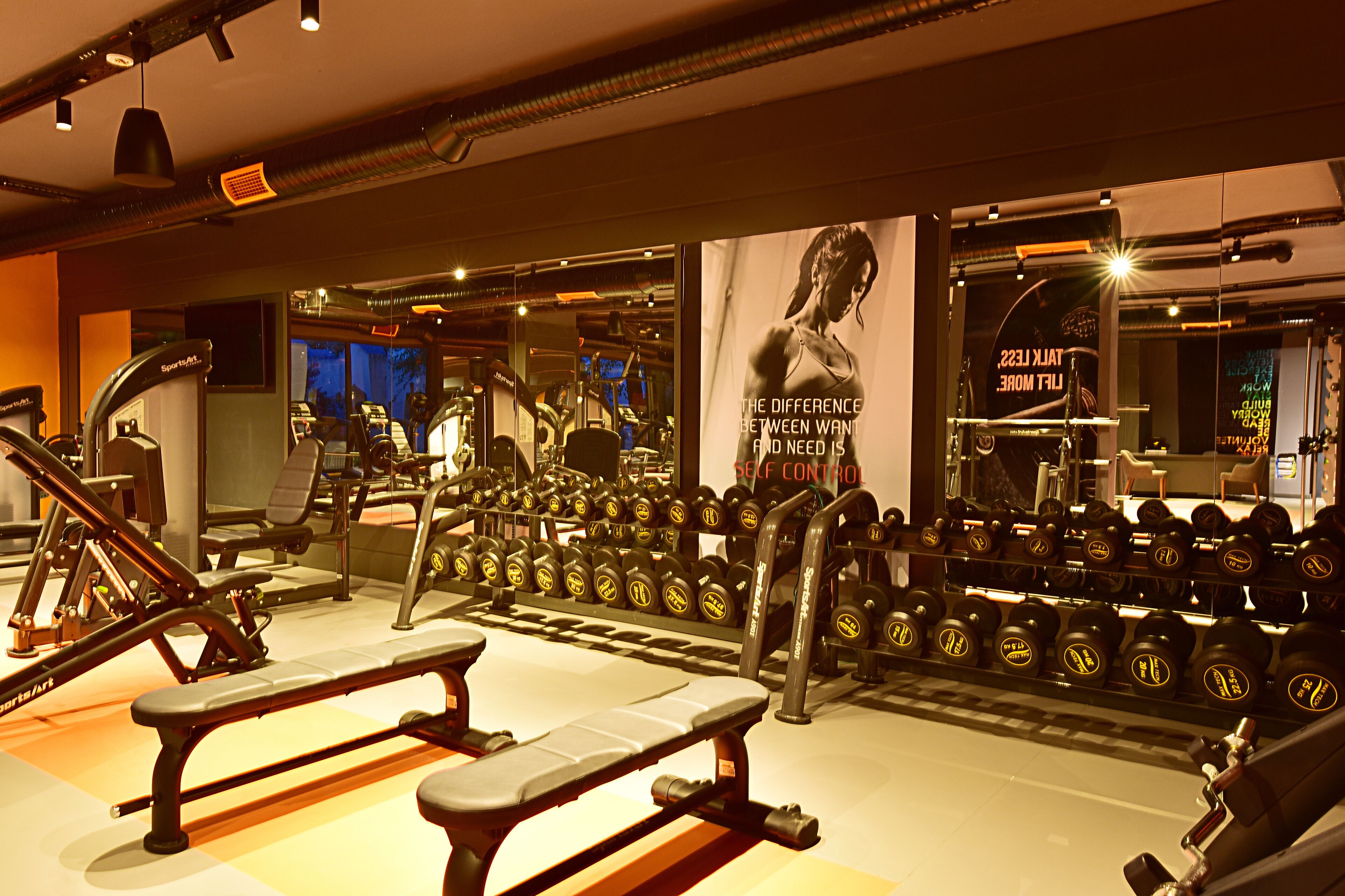 A gym with various exercise equipment, including benches and dumbbells.