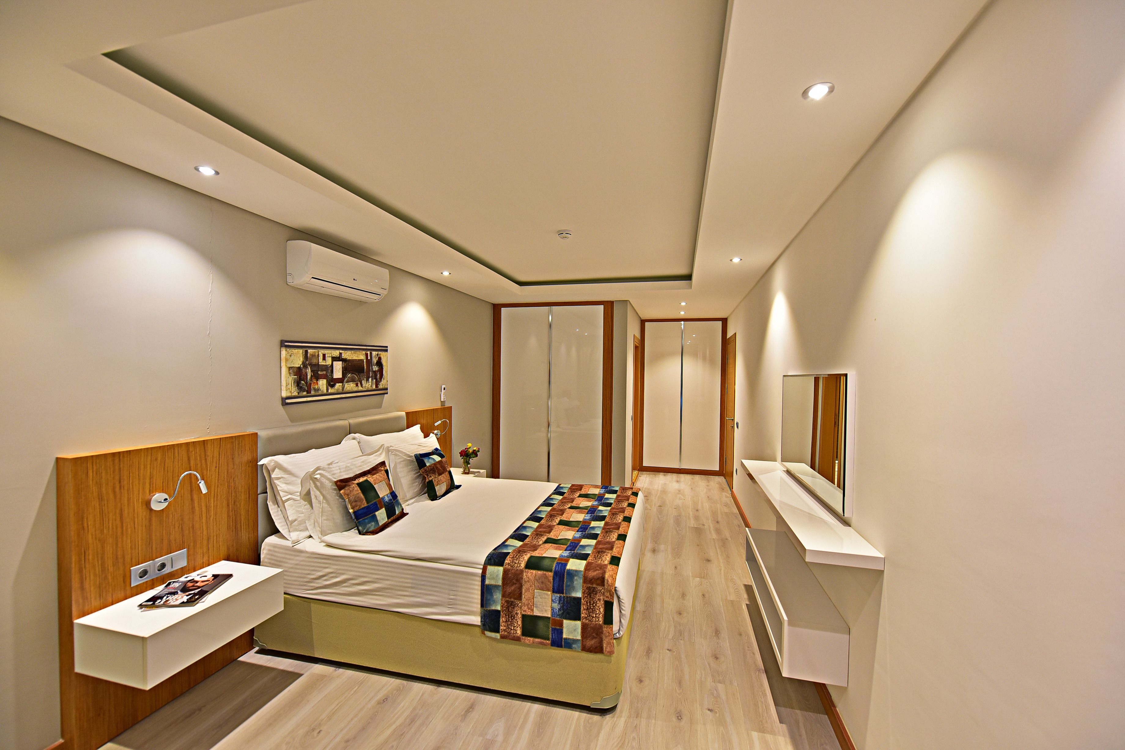 Een moderne slaapkamer met een bed, nachtkastje en een ingebouwde televisie.