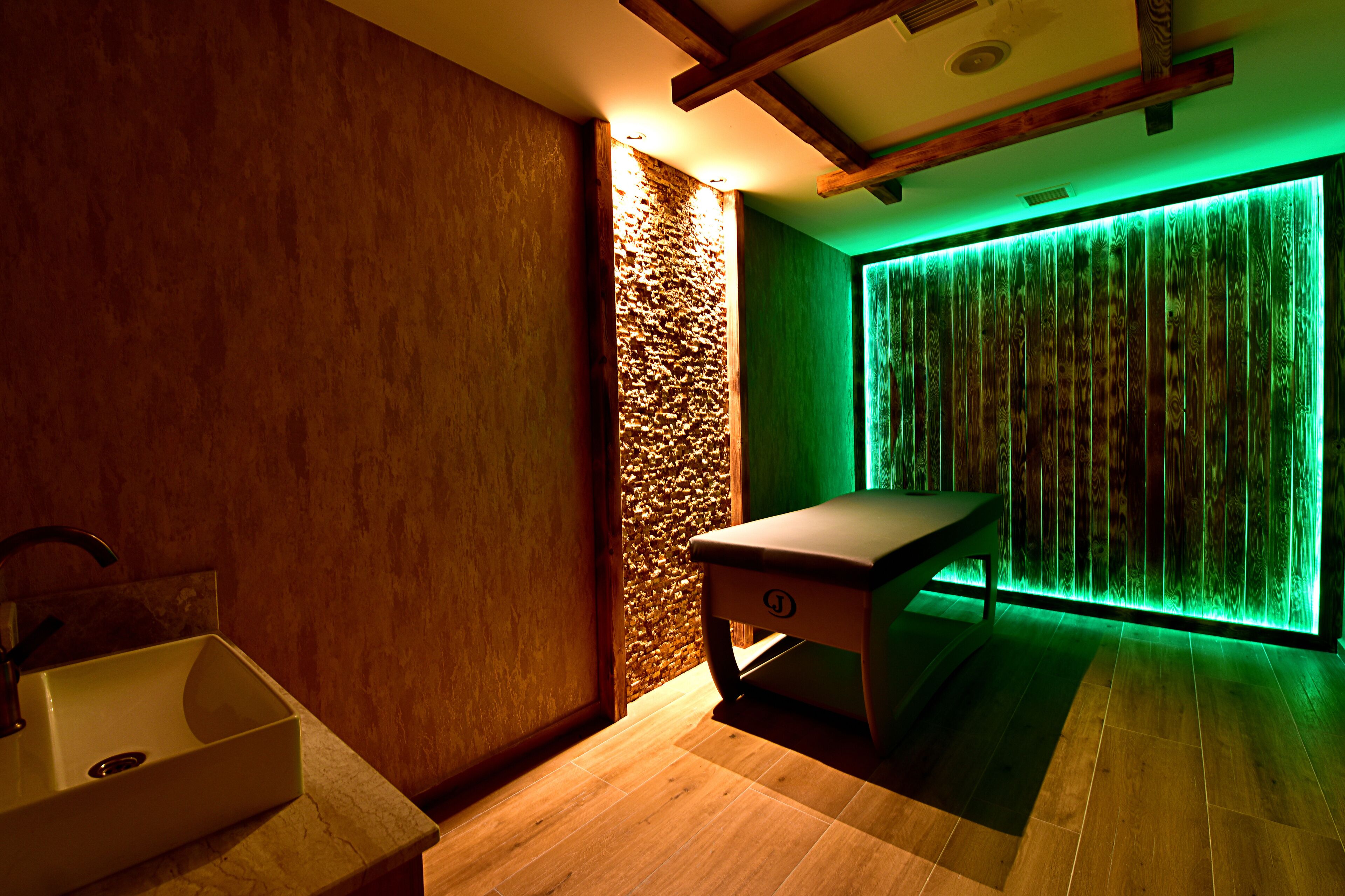 A spa room with a wooden bench, a sink, and a wall with vertical wooden slats.