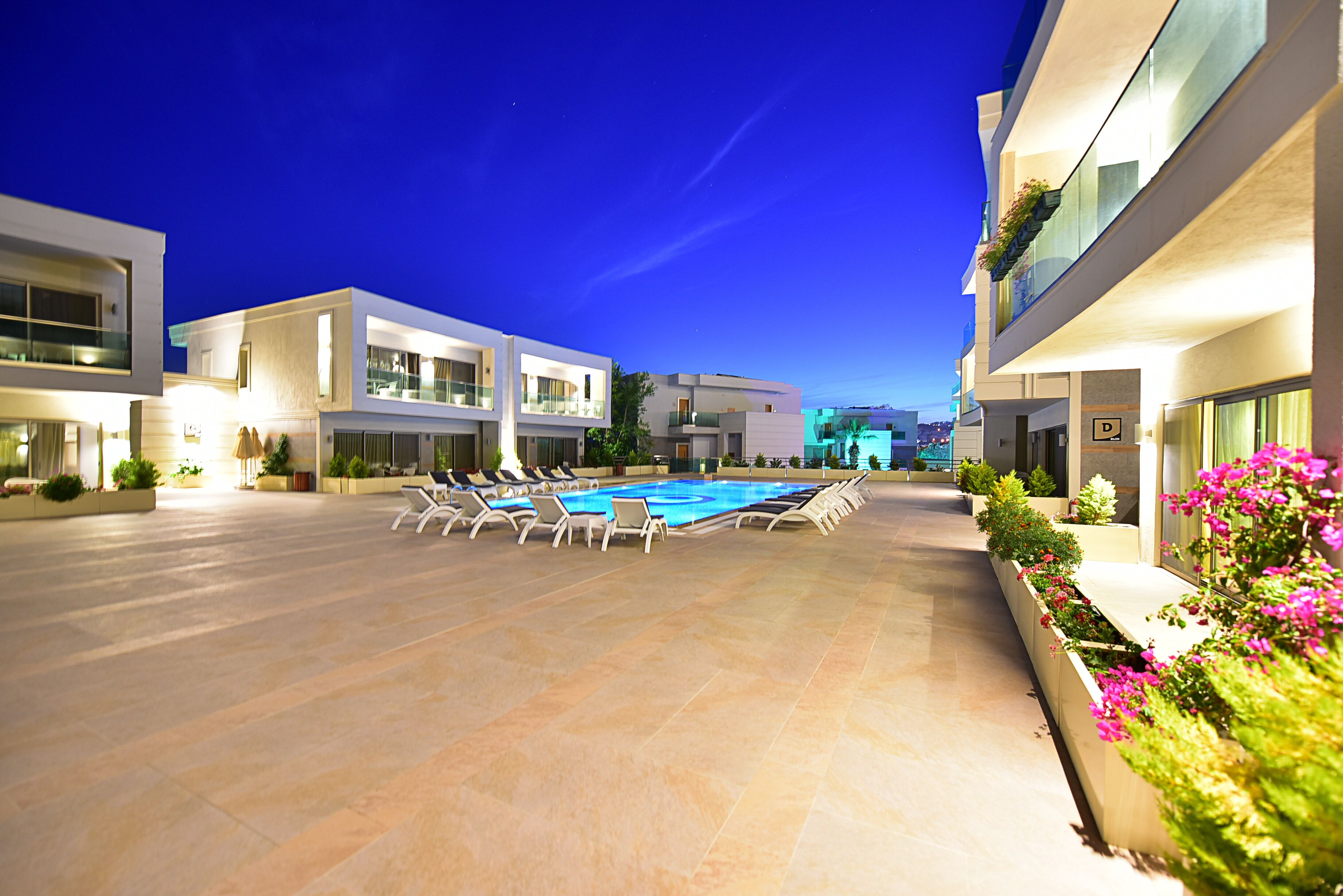 A modern hotel with a swimming pool, lounge chairs, and well-maintained landscaping.