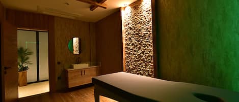 Un baño moderno con suelo de madera, un lavamanos grande y una pared decorativa de piedra.
