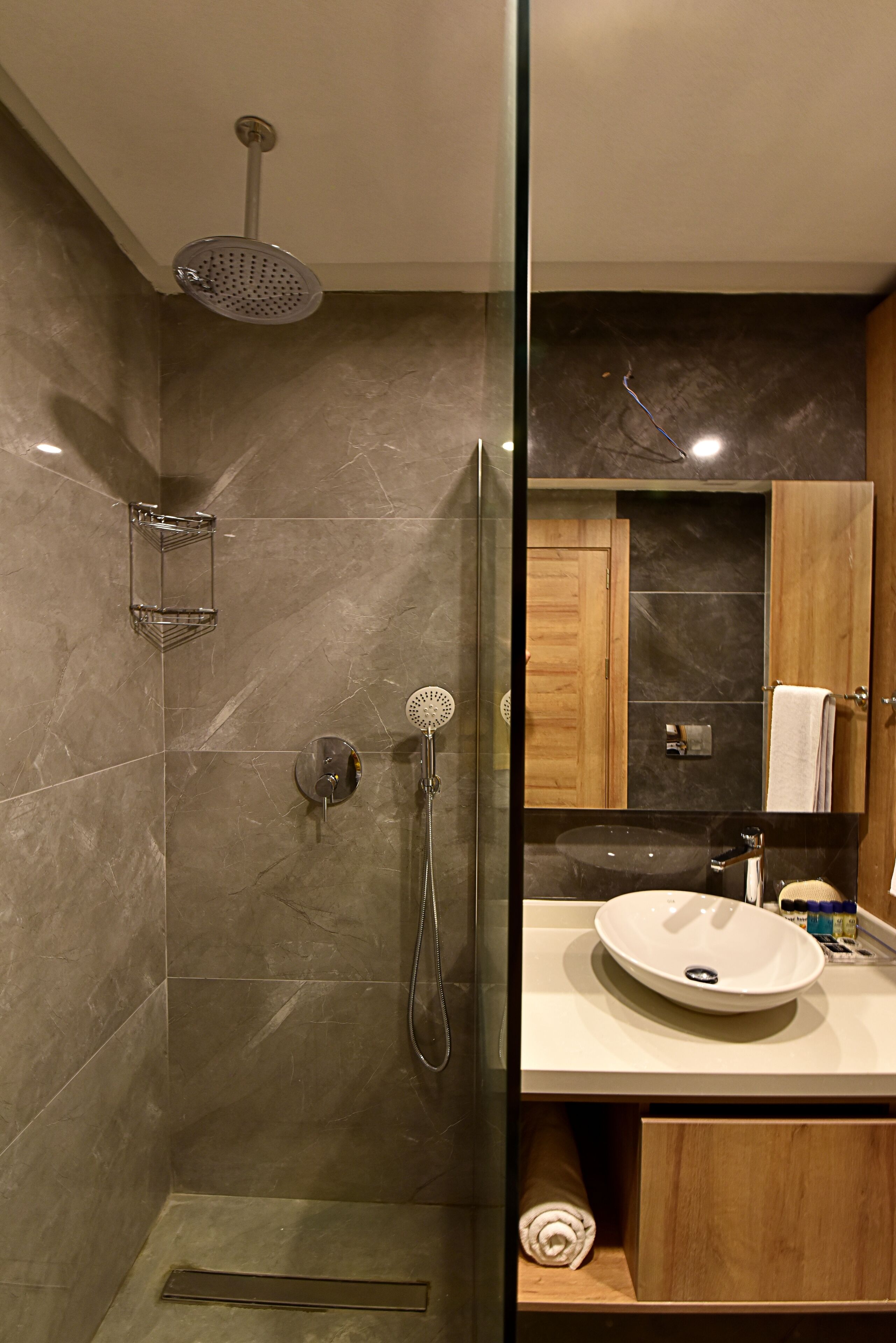 A modern bathroom with a glass-enclosed shower, a white sink, and wooden cabinets.