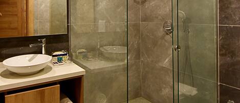 A modern bathroom with a glass-enclosed shower, a wooden vanity, and a marble-tiled floor.
