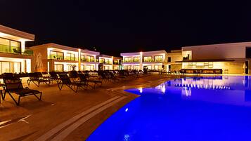 A hotel with a swimming pool, lounge chairs, and a restaurant named "The Mako Bar".