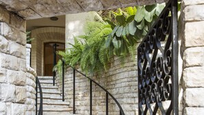 Un vélo blanc est garé à côté d’un mur de pierre, avec une porte en métal et un escalier menant à un niveau supérieur.