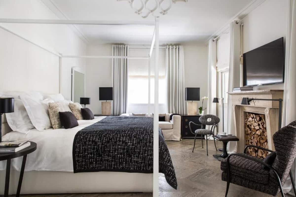 Habitación de hotel con cama, televisor, chimenea y zona de estar.