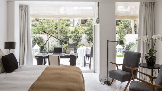 Une chambre d’hôtel avec un lit, un bureau avec un ordinateur portable, une chaise et une vue sur l’extérieur.
