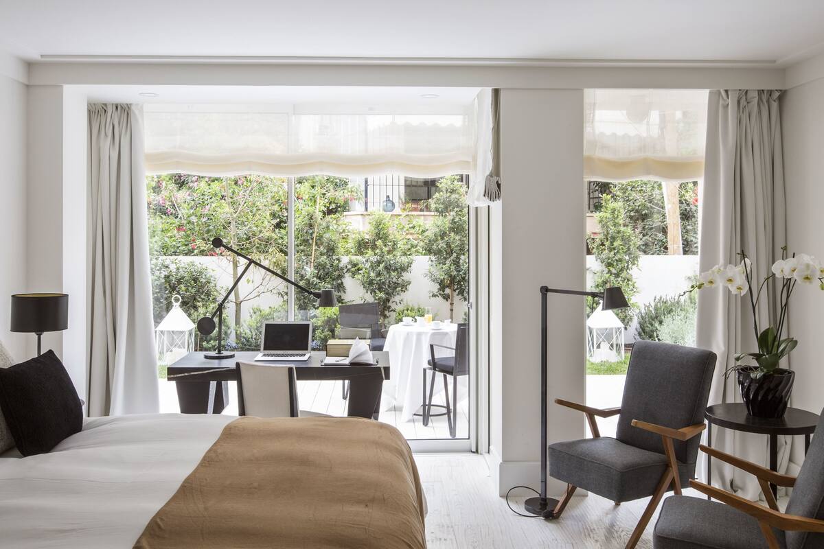 Habitación de hotel con cama, escritorio, computadora portátil, una silla y vistas al exterior.