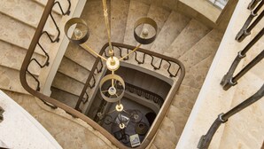 Un escalier en colimaçon avec un espace central ouvert, des rampes en métal et un lustre.