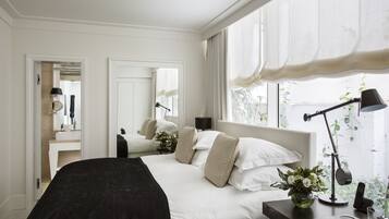 Un dormitorio moderno con una cama grande, mesitas de noche, un escritorio con lámpara y una ventana con cortinas.