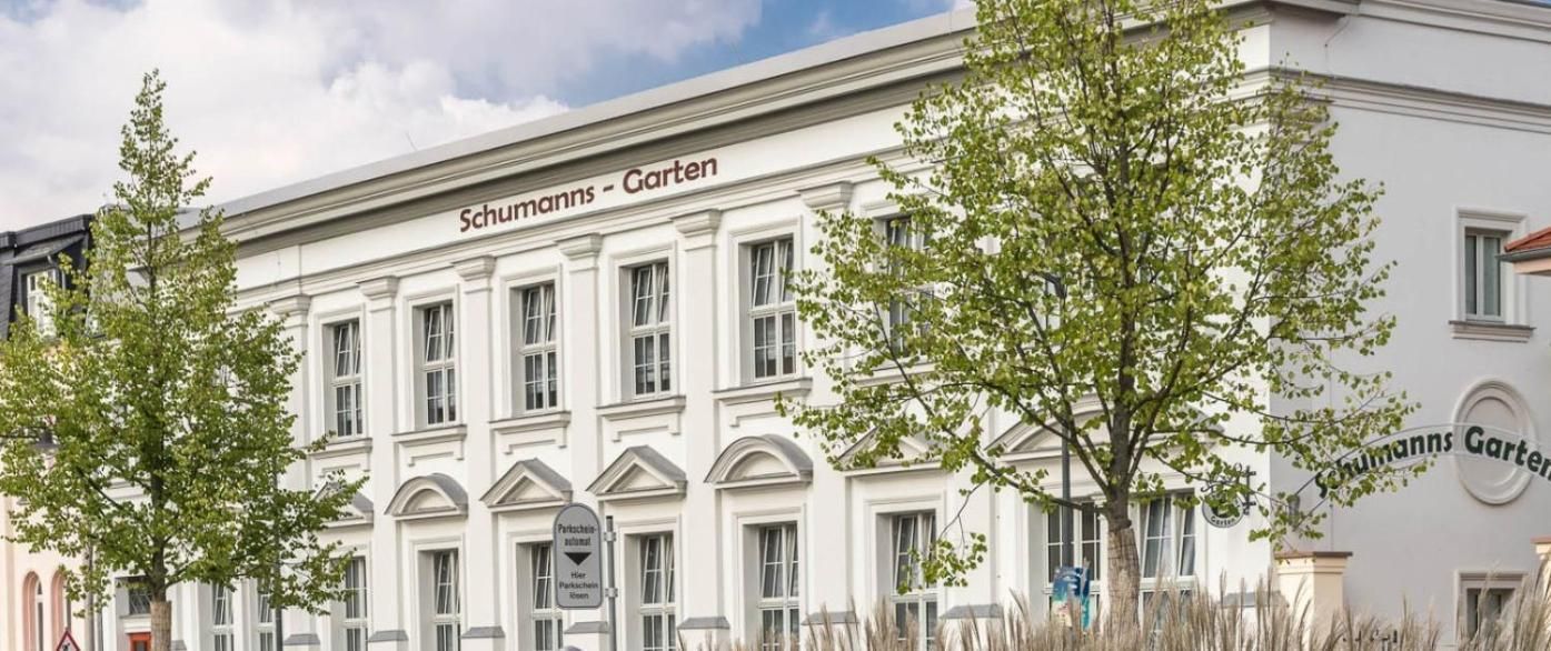 A building with the sign 'Schumann's Garten' indicating a garden or park area.