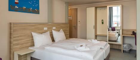 A hotel room with a bed, a nightstand, a mirror, and a painting on the wall.