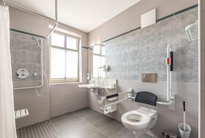 A modern bathroom with a shower, toilet, and hand dryer.