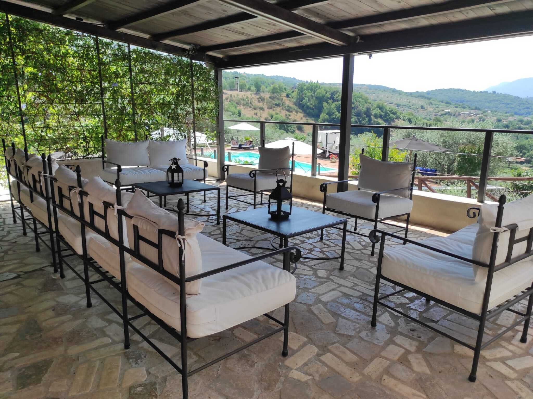 Un'area relax all'aperto coperta, con vista su una piscina e delle colline.